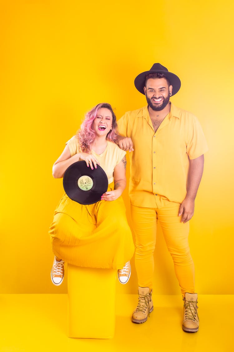 Smiling Couple In Yellow Clothes Posing In Yellow Studio