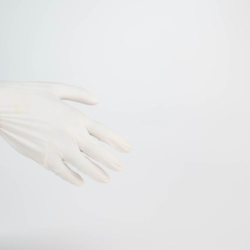 Free A single latex gloved hand extends against a white background, providing ample copy space. Stock Photo
