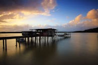 宁静的日落下，平静的湖面上坐落着一个乡村码头，唤起平静与孤独之感