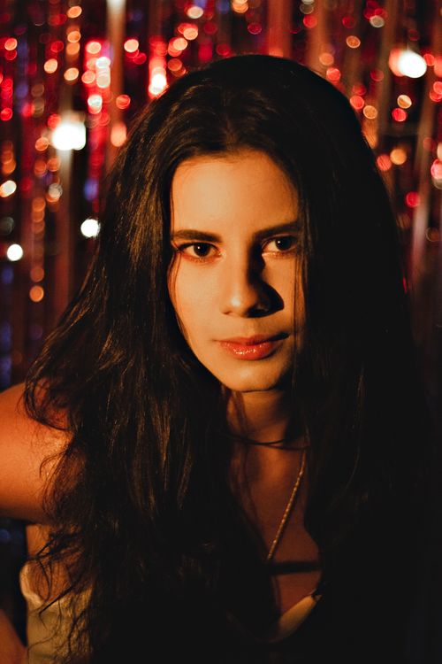 Free Elegant portrait of a woman with long hair and captivating eyes, set against a festive backdrop. Stock Photo