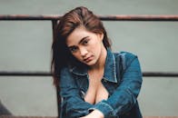 一位表情沉思、身穿牛仔夹克的女性肖像，背景为户外