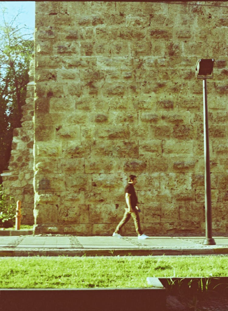 A Man Walking On Sidewalk