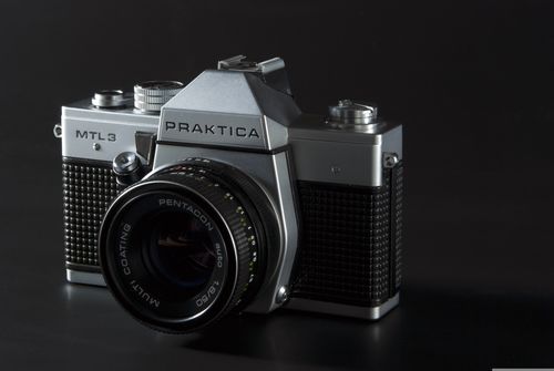 Free Close-up of a vintage Praktica MTL3 SLR camera with a Pentacon lens against a black background. Stock Photo