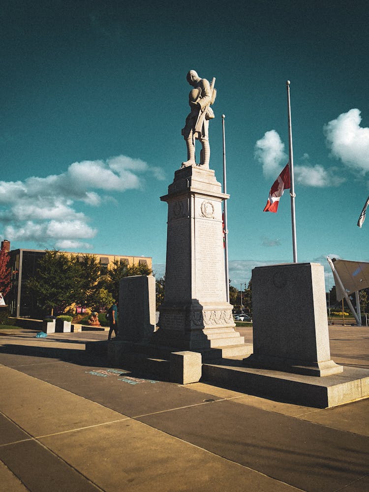 Statue On A Pedestal Near Half-Mast Flags