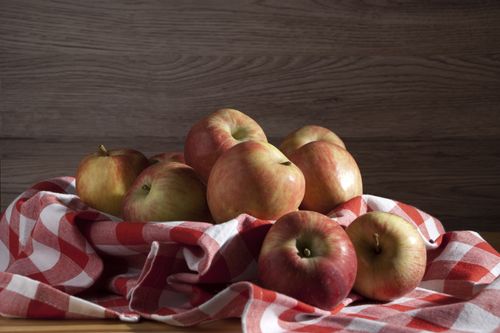 Free A close-up view of fresh apples sitting on a red checkered cloth indoors. Stock Photo