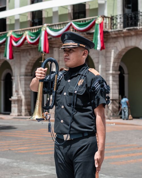 Free A soldier in uniform holding a trumpet in a Mexican festival with colorful decorations. Stock Photo