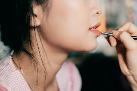 Close-up of a woman applying lipstick, showcasing beauty and cosmetics.