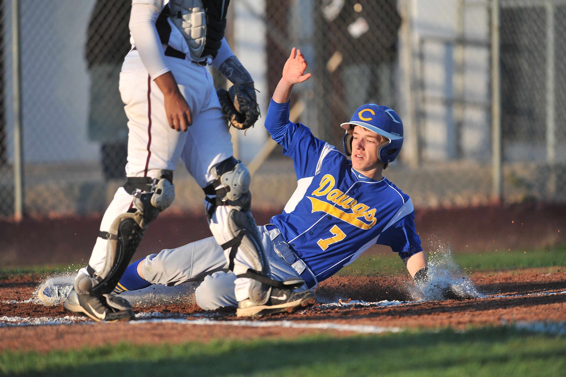 Baseball player sliding hard into home during a competitive game