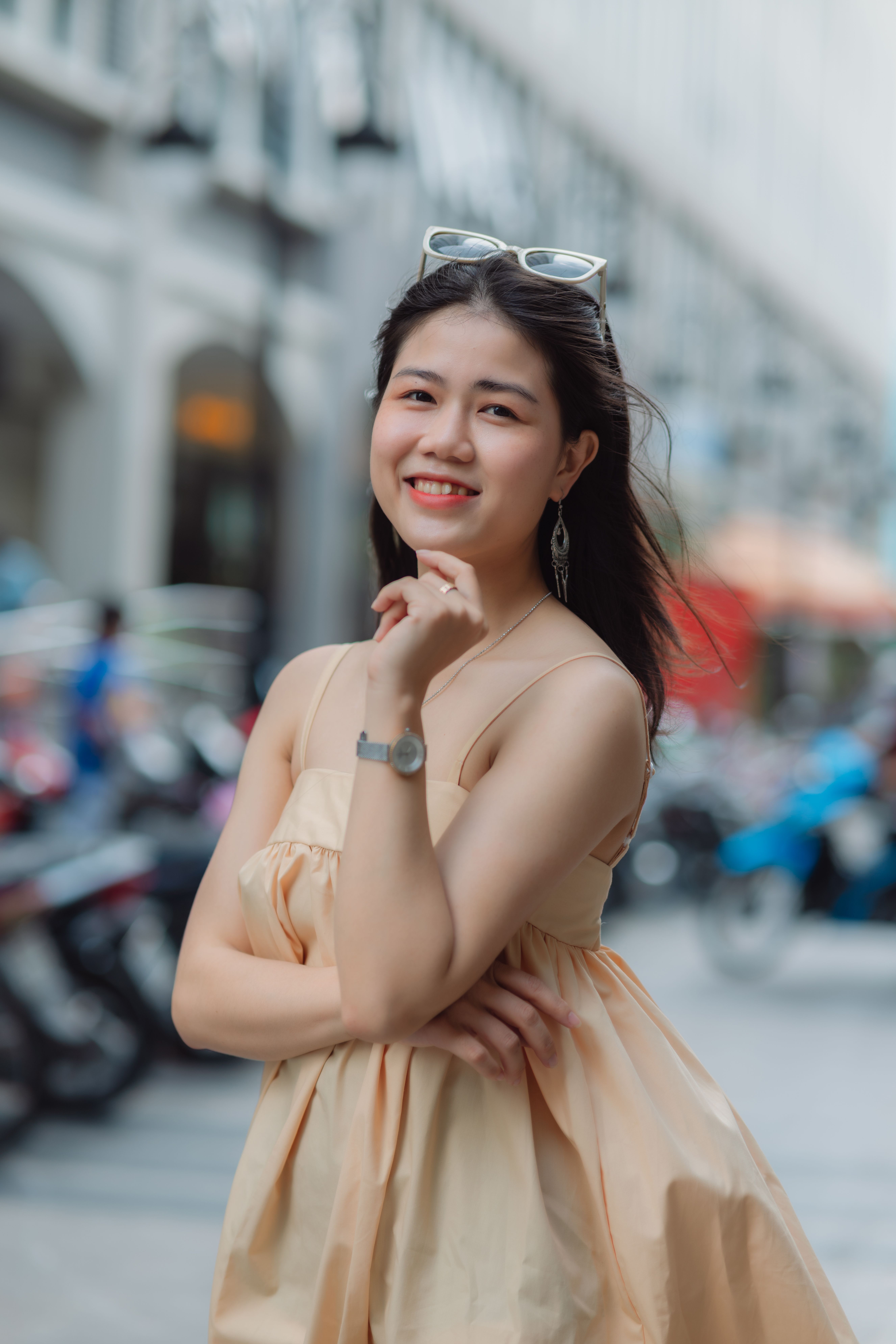 Beautiful woman smiling in a summer dress on a lively street with soft focus background.