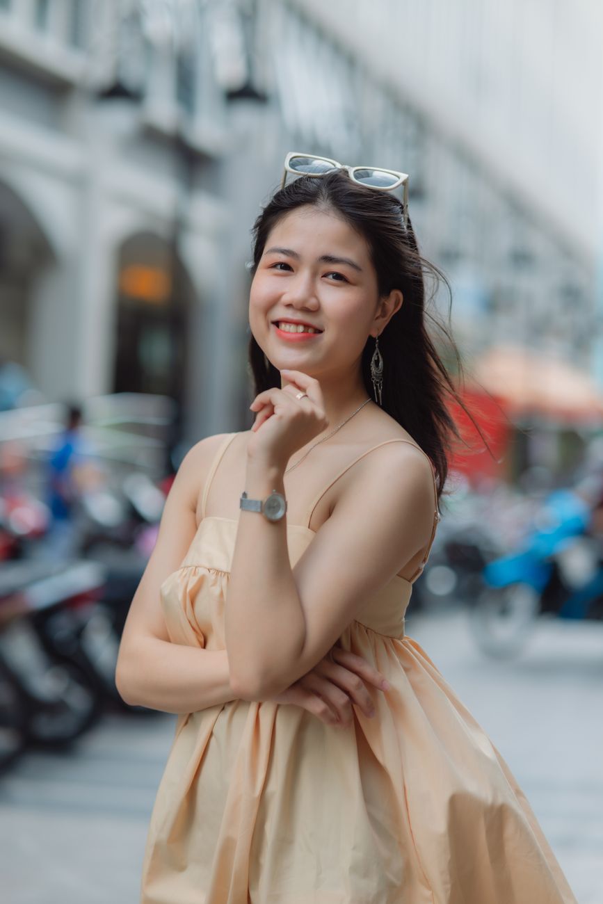 Beautiful woman smiling in a summer dress on a lively street with soft focus background.