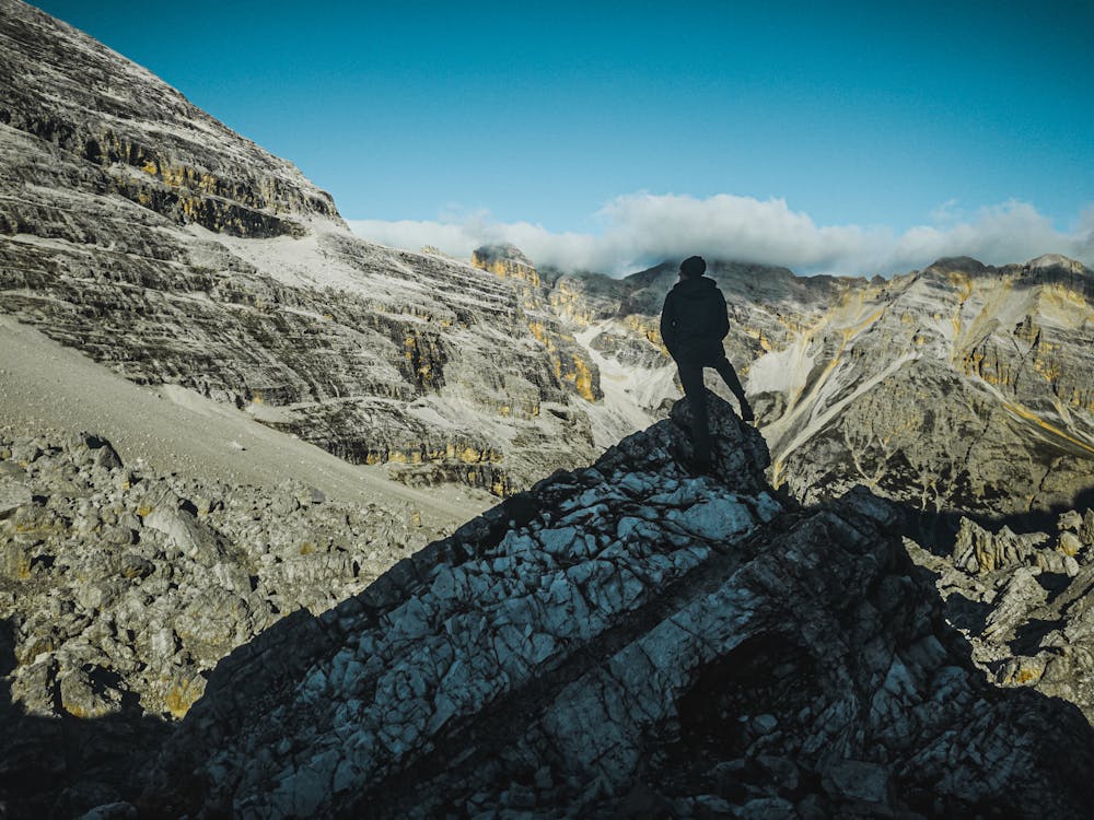 A Person Standing at the Peak of a Rocky Mountain