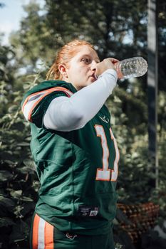 Athlete in sports uniform drinking water outdoors in Ciudad de México, capturing a hydration break.
