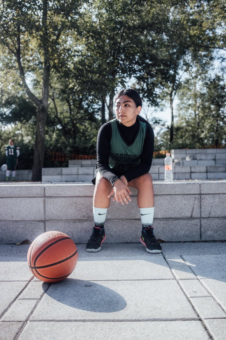 Woman Wearing Activewear Sitting Beside A Ball