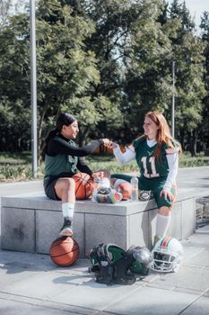 Two women in sportswear fist bump while sitting outdoors in Ciudad de México.