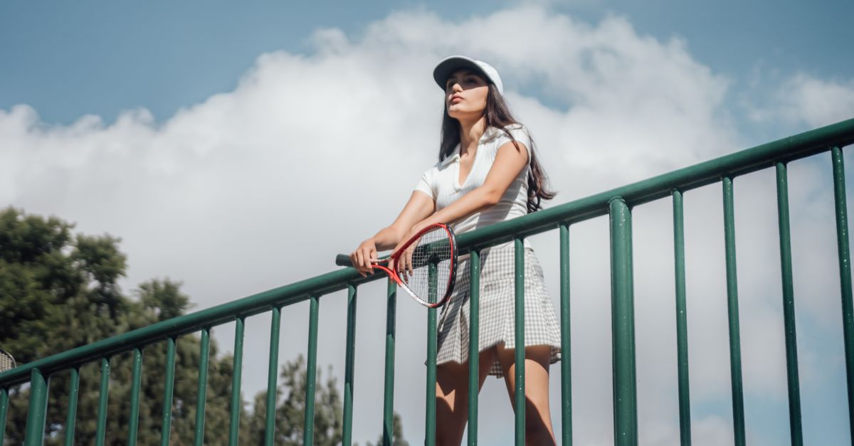 Woman Holding a Tennis Racket Leaning on a Railing · Free Stock Photo