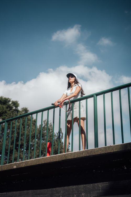 Woman Holding a Tennis Racket Leaning on a Railing · Free Stock Photo