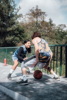 Two athletes engage in a heated outdoor basketball match in Ciudad de México, showcasing skill and competition.