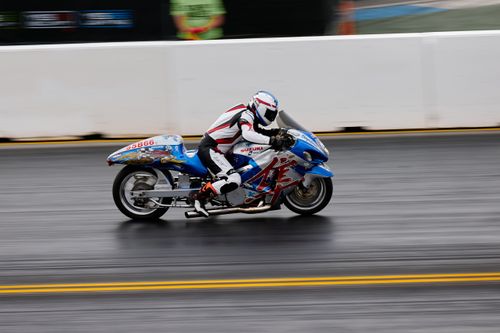 Free Dynamic panning shot of a motorcycle racer speeding on a track during a motorsport competition. Stock Photo