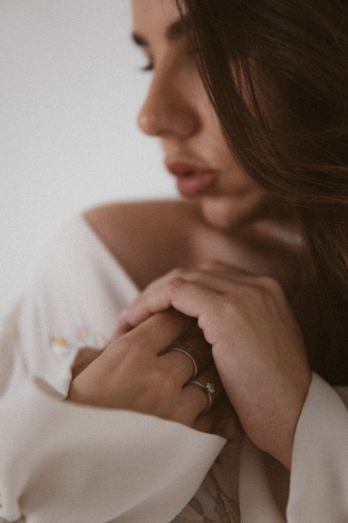 Free Soft focus portrait of a woman with delicate hands adorned with rings, evoking elegance. Stock Photo
