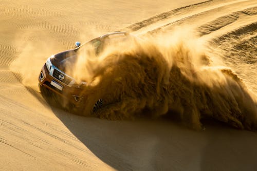 Red Nissan Vehicle Running on Sand Dune