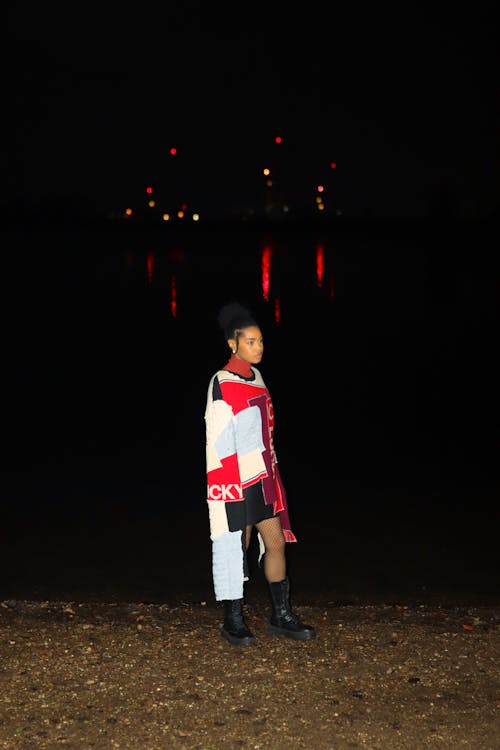 A Woman in Printed Dress Standing Near the Lake at Night