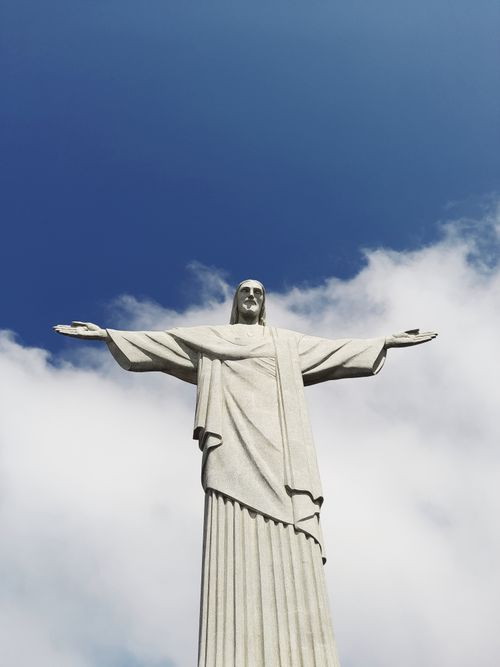 Free Christ the Redeemer statue in Rio de Janeiro with arms open against a clear blue sky. Stock Photo