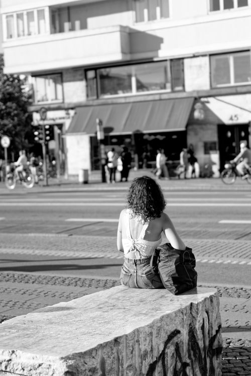 Free Woman sitting on a bench capturing Copenhagen's street life in black and white. Stock Photo