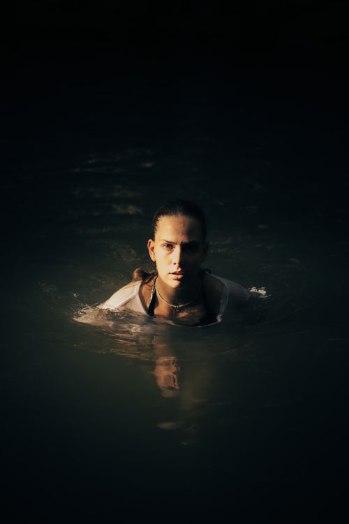 Free A serene portrait of a woman swimming in a dark lake at night, with soft lighting. Stock Photo