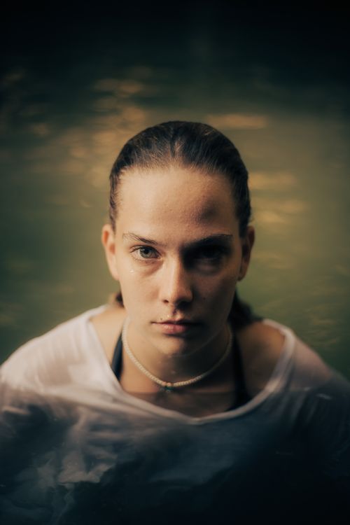 Free Emotive portrait of a woman outdoors, partially submerged in water, exuding tranquility. Stock Photo
