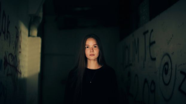 Portrait of a woman in a dimly lit urban alley, conveying mystery and introspection.