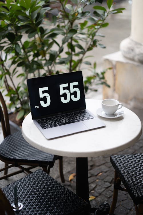 Laptop with Time on Screen on Cafe Table Outdoors