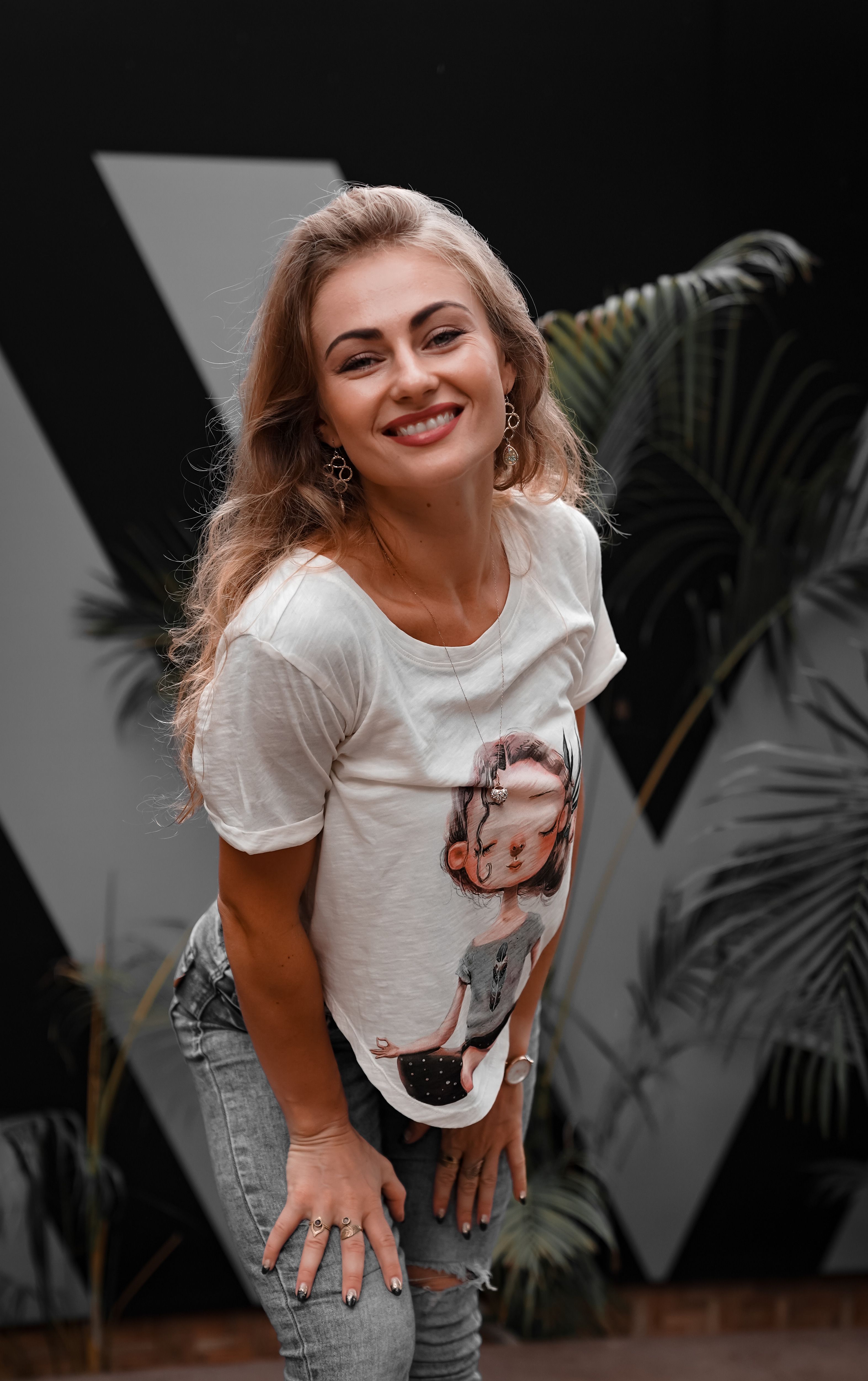 Happy woman posing confidently in a casual outfit with a tropical background.