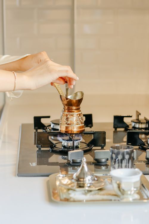 Free Hands preparing Turkish coffee in a copper cezve on a modern stove, perfect for lifestyle and culinary themes. Stock Photo