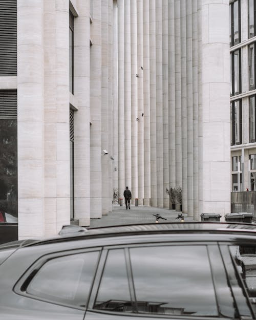 Man Walking near Buildings with Columns