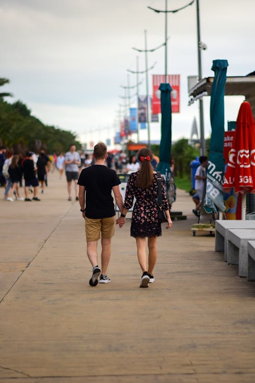 Back View of Man and Woman Holding Hands while Walking