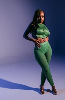 A fashionable woman in a chic green outfit poses confidently in a studio setting.