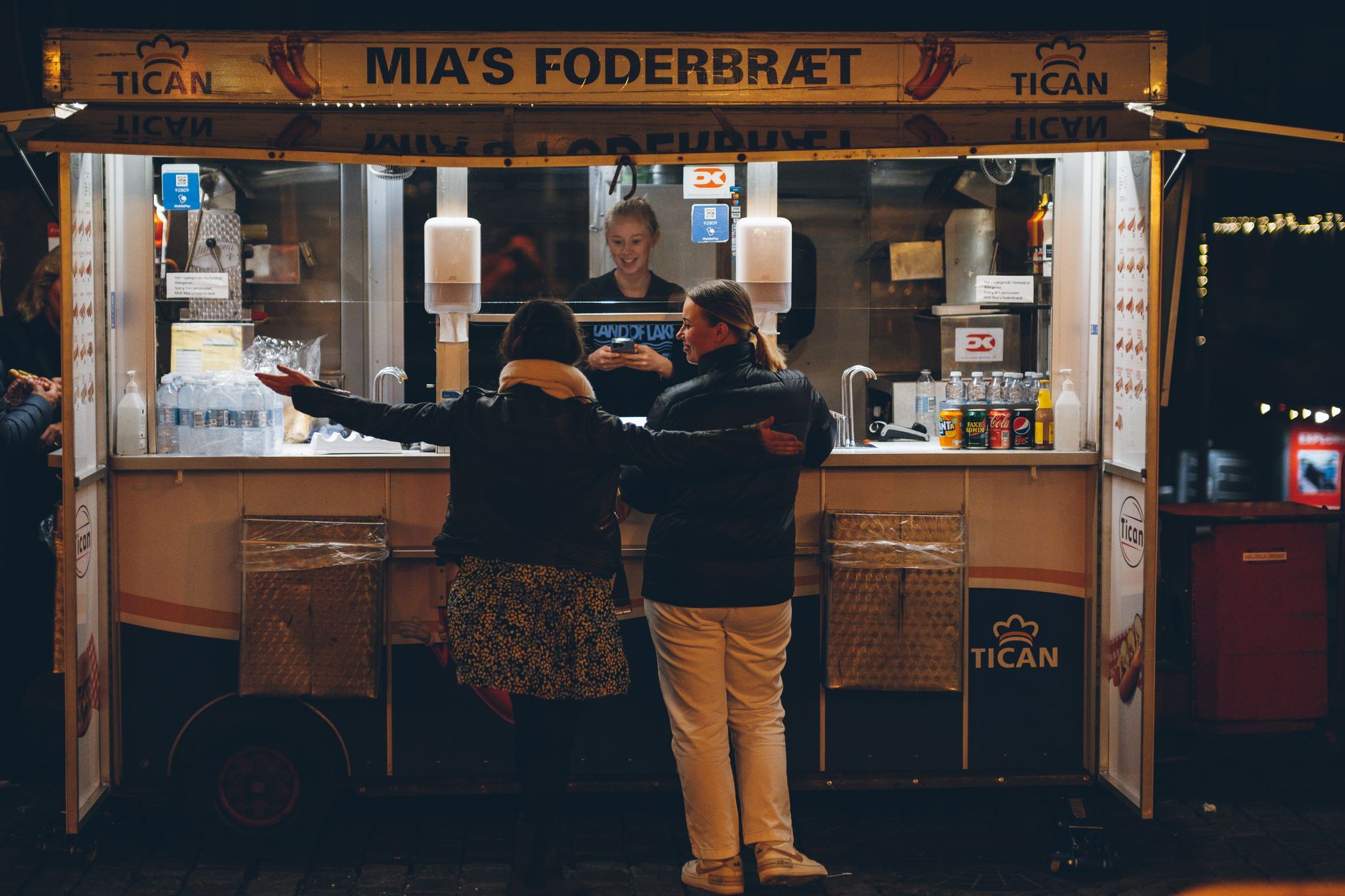 Women buying food at a street stand at night in Copenhagen, Denmark.