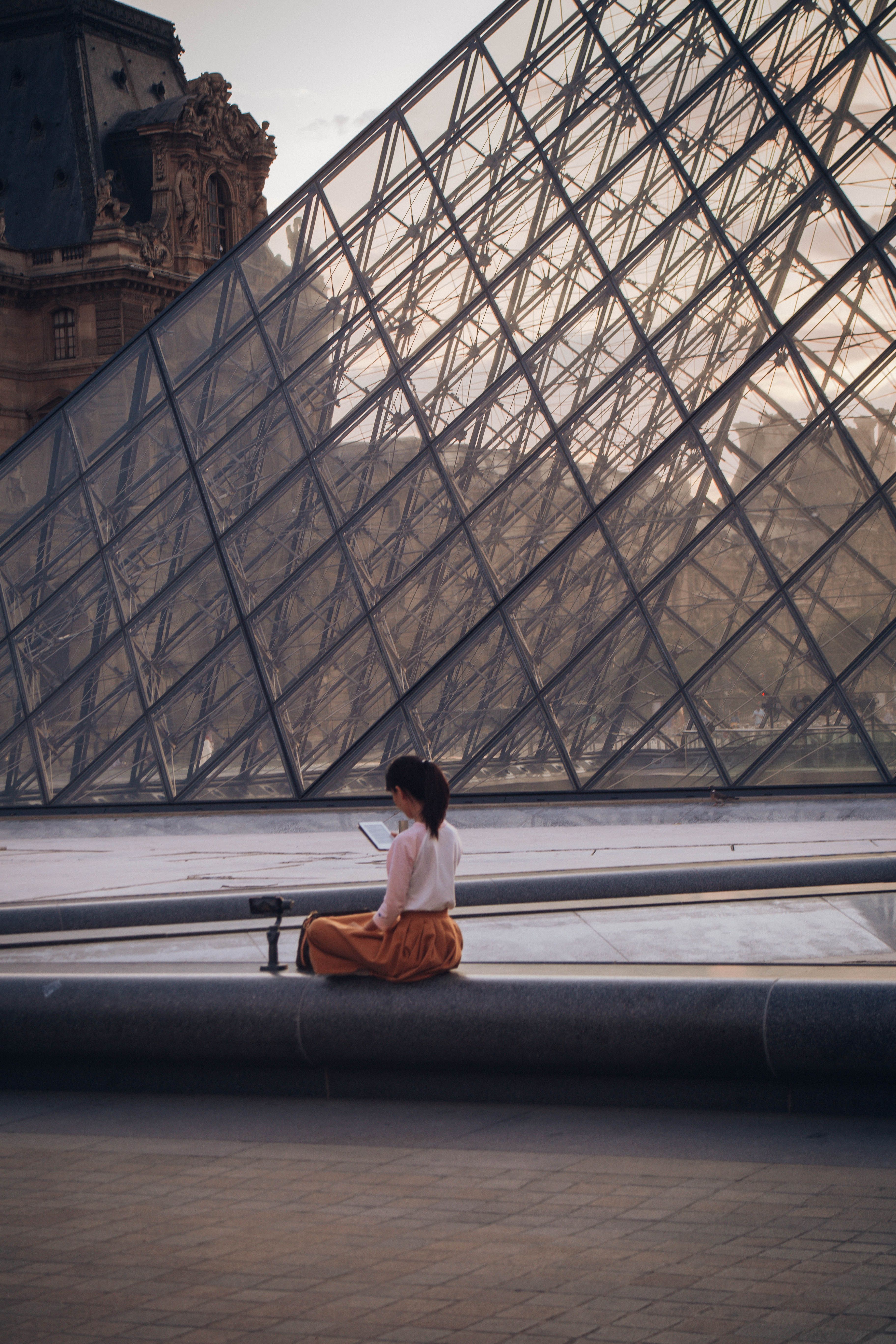A Woman in White Long Sleeves Sitting Beside the Louvre Museum · Free ...