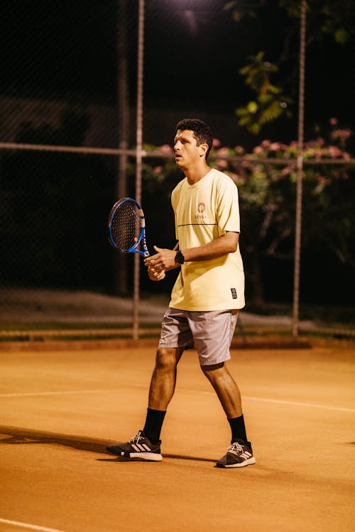 Man in Yellow Shirt Holding a Tennis Racket