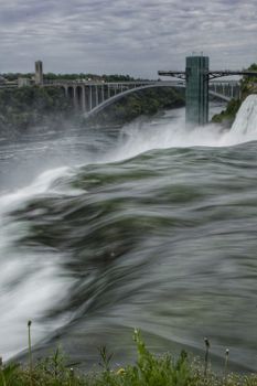 A breathtaking capture of Niagara Falls with the iconic Rainbow Bridge in the background.