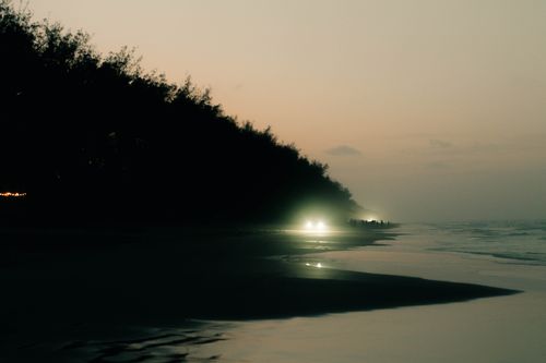 Free Tranquil seashore scene in Tuxpan de Rodríguez Cano, Mexico, illuminated by glowing vehicle headlights at dusk. Stock Photo
