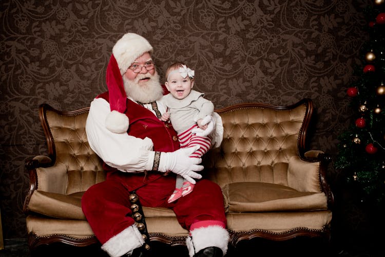 Man In Santa Claus Costume Holding A Baby Girl