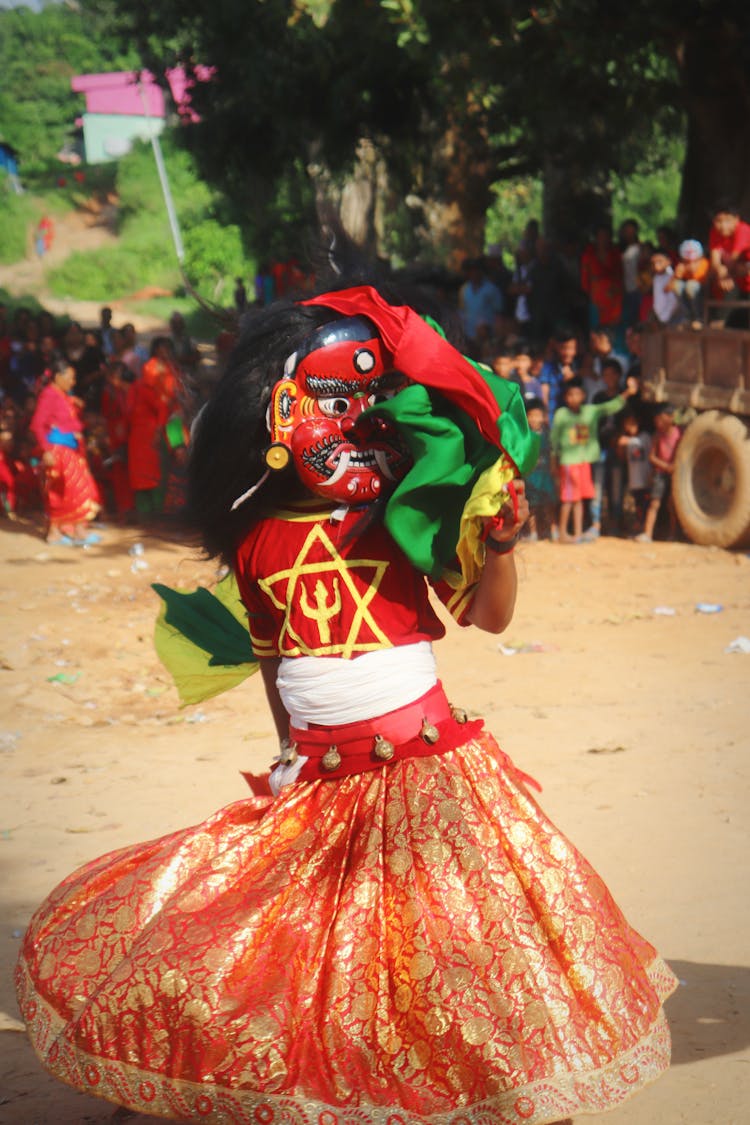 A Person Dancing In A Mask And A Costume 