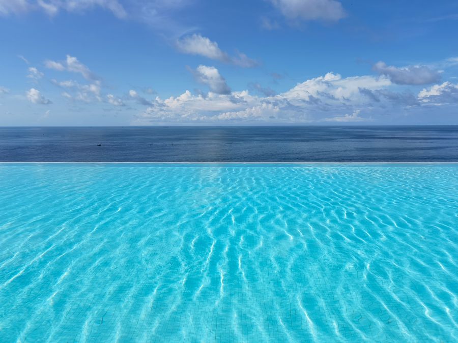 Serene infinity pool blending with ocean horizon under a clear blue sky