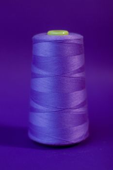 Close-up of vibrant purple thread spool on matching purple background.