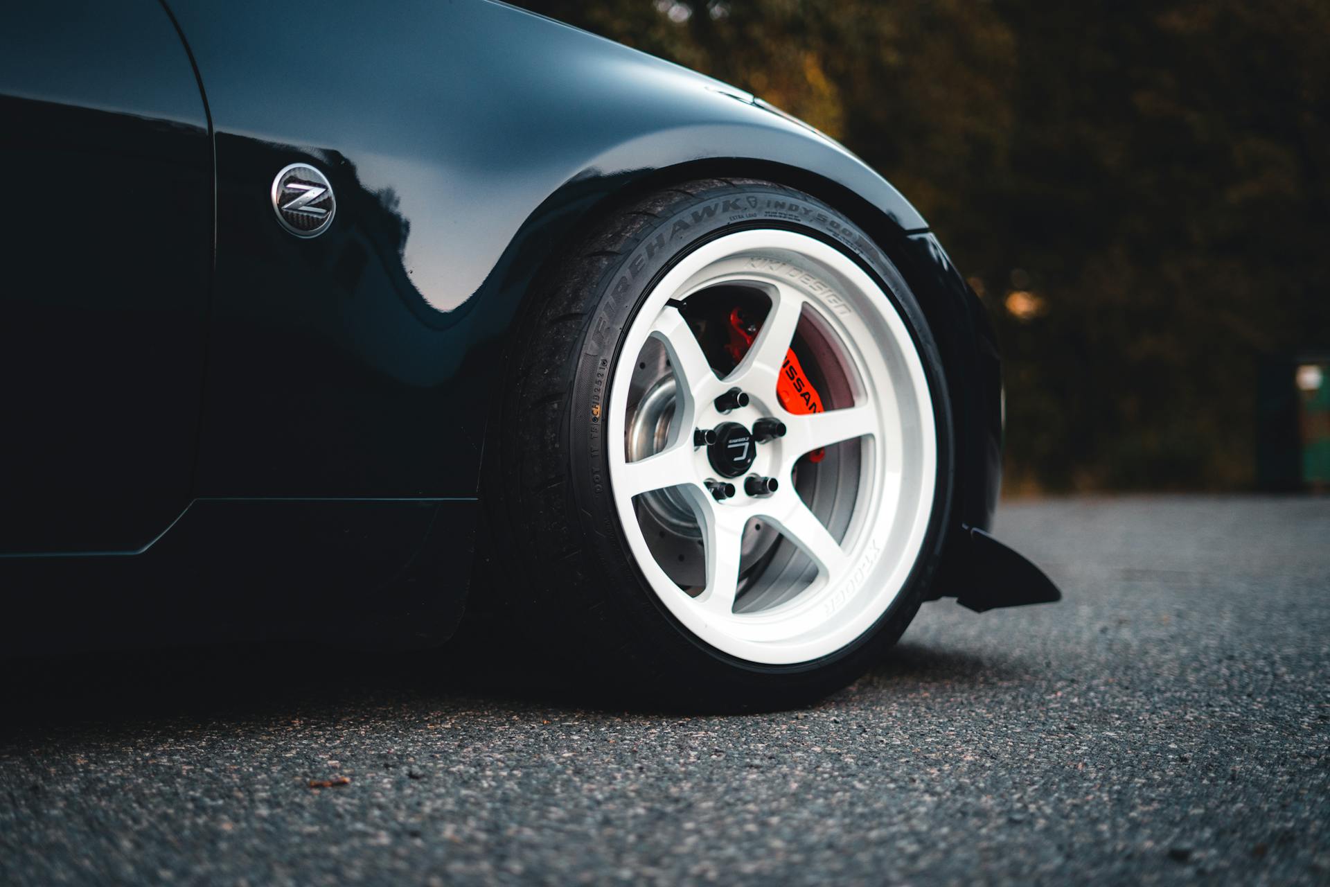 A detailed view of the wheel and rim on a sleek black sports car parked on asphalt.