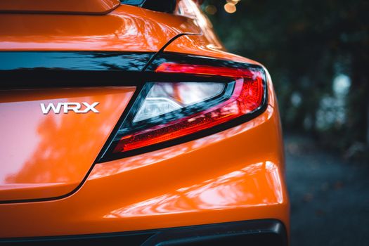 Detailed rear view of a Subaru WRX showcasing the tail light and sleek orange finish. Ideal for automotive themes.
