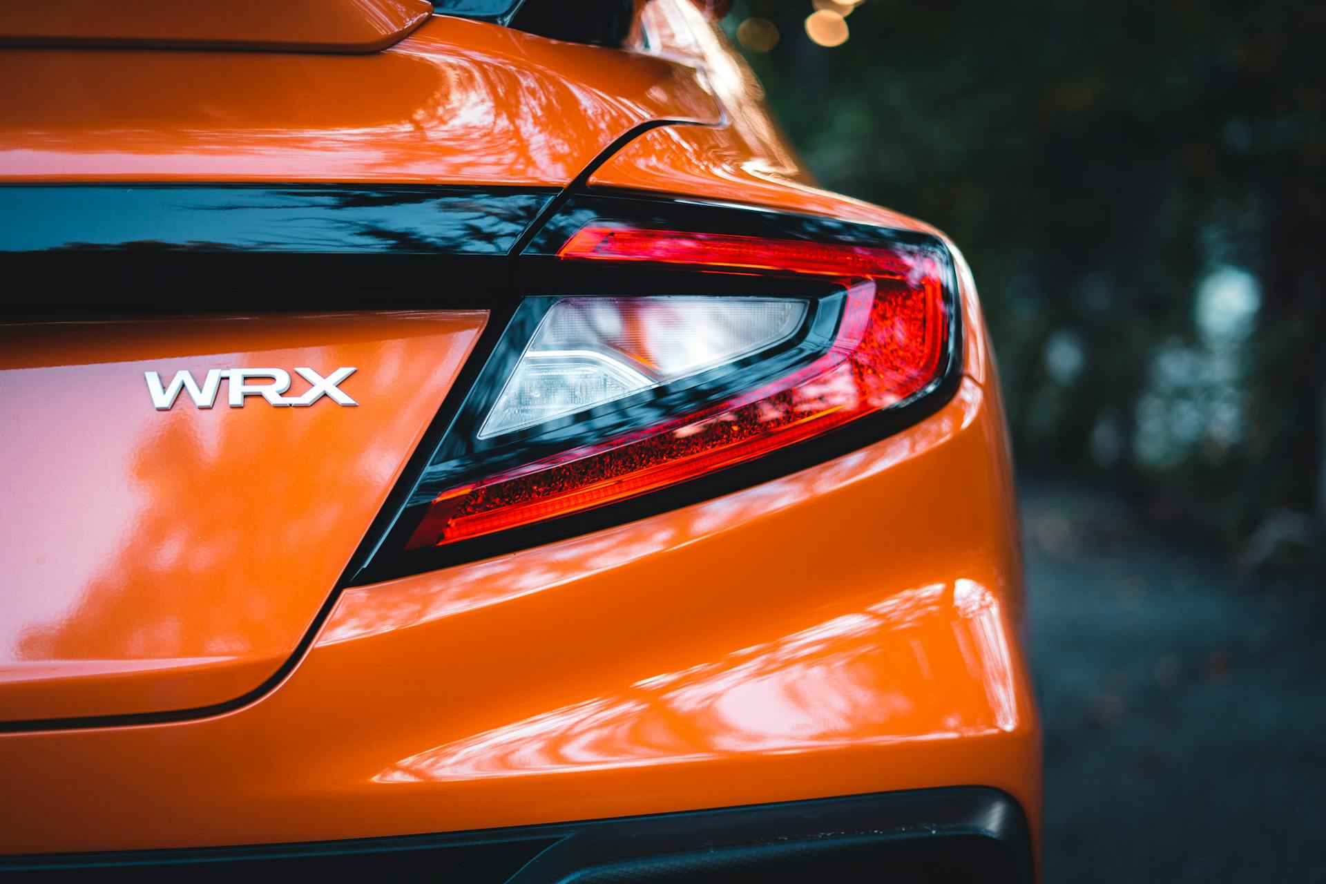 Detailed rear view of a Subaru WRX showcasing the tail light and sleek orange finish. Ideal for automotive themes.