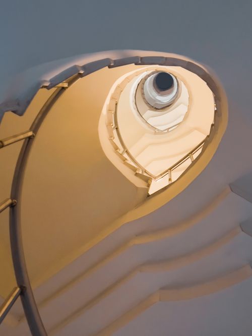 Free A mesmerizing vertical shot of a white spiral staircase, showcasing architectural elegance in an interior setting. Stock Photo