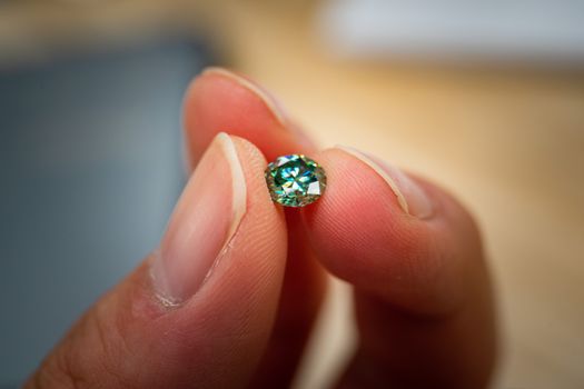A detailed macro shot of a green diamond held between fingertips, showcasing clarity and brilliance.